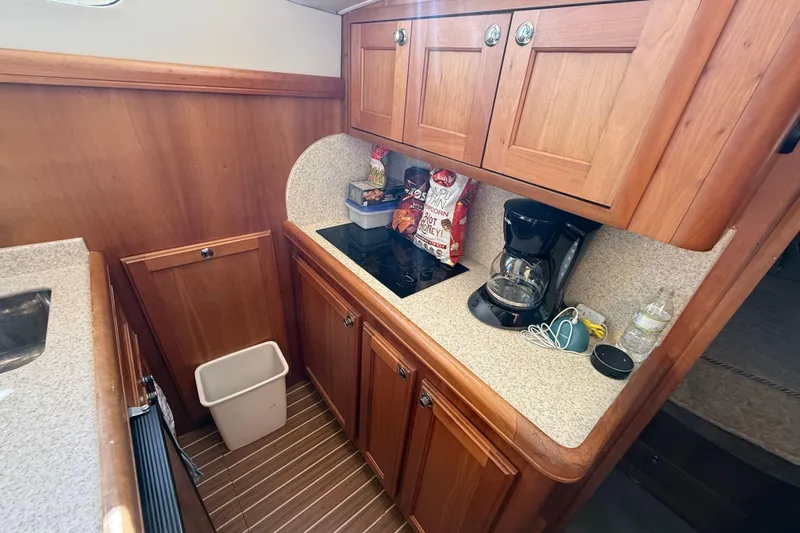  Yacht Photos Pics 2006 Mainship 34 Trawler galley with wooden cabinets, countertop, and coffee maker.