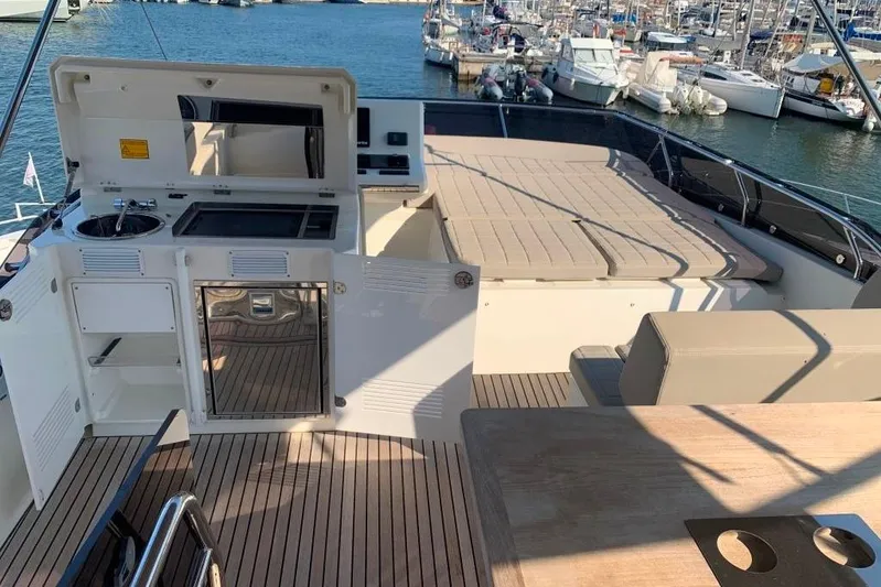 Fly Away Yacht Photos Pics Luxurious 2018 Prestige 520 yacht deck with kitchenette and sunbathing area in marina setting.