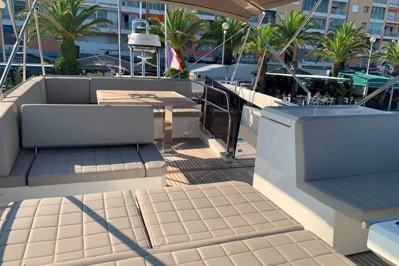 Fly Away Yacht Photos Pics Luxurious 2018 Prestige 520 yacht deck with seating, table, and palm trees in the background.