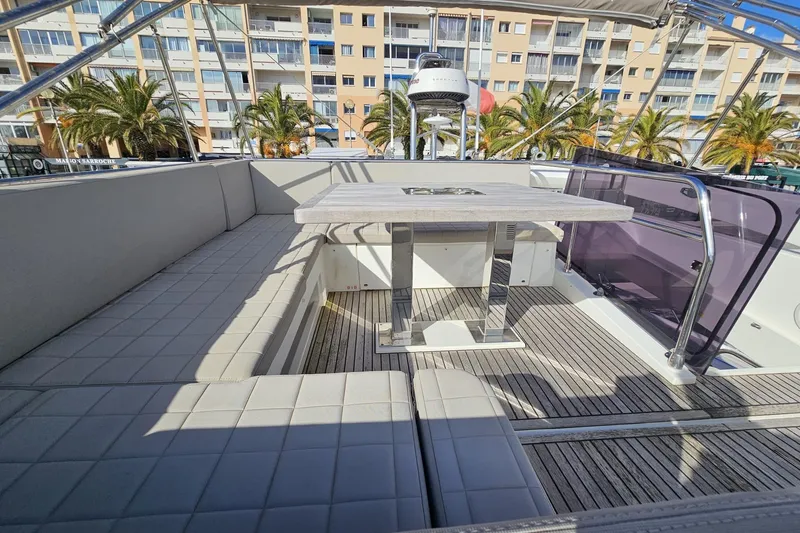 Fly Away Yacht Photos Pics Luxurious 2018 Prestige 520 yacht deck with seating and table, docked near palm trees.