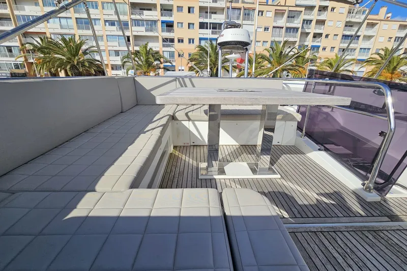 Fly Away Yacht Photos Pics Luxurious 2018 Prestige 520 yacht deck with seating and table, docked near palm trees.