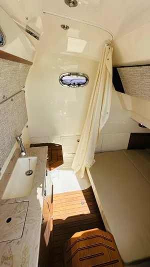  Yacht Photos Pics 2023 Boston Whaler 360 Outrage cabin interior with sink, bed, and wooden flooring.