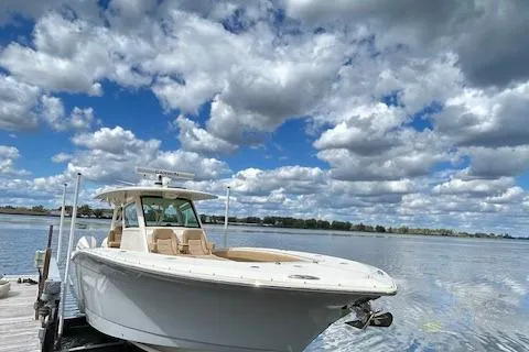 Seas Today Yacht Photos Pics 2019 Scout 355 LXF boat docked on a serene lake under a cloudy sky.