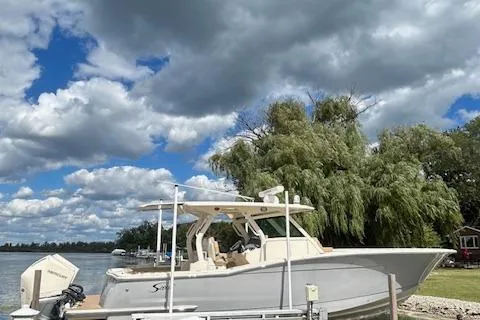 Seas Today Yacht Photos Pics 2019 Scout 355 LXF boat docked by a scenic lakeside with cloudy sky.