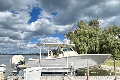 Seas Today Yacht Photos Pics 2019 Scout 355 LXF boat docked by a scenic lake under a cloudy sky.
