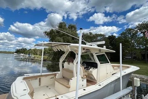 Seas Today Yacht Photos Pics 2019 Scout 355 LXF boat docked by a scenic lake under a cloudy sky.