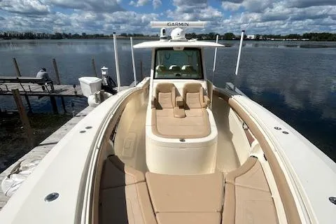 Seas Today Yacht Photos Pics 2019 Scout 355 LXF boat docked by a serene lake under a cloudy sky.