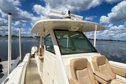Seas Today Yacht Photos Pics 2019 Scout 355 LXF boat with tan seating, docked by a serene lake under a cloudy sky.