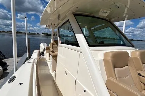 Seas Today Yacht Photos Pics 2019 Scout 355 LXF boat docked by a serene waterfront under a cloudy sky.