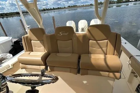 Seas Today Yacht Photos Pics 2019 Scout 355 LXF boat with tan leather seating and steering wheel, docked by a lake.