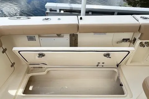 Seas Today Yacht Photos Pics 2019 Scout 355 LXF boat with open storage compartment, beige seating, and water in the background.