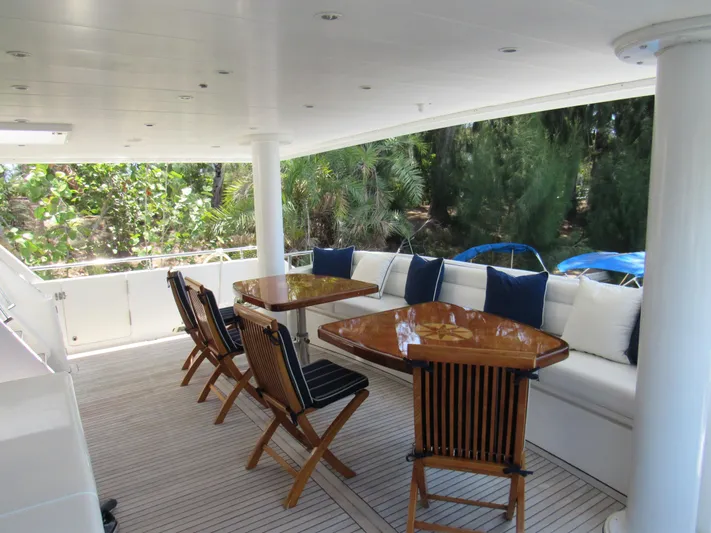 Sanctuary Yacht Photos Pics Outdoor seating area on 2002 Hargrave Raised Pilothouse yacht with wooden tables and chairs.