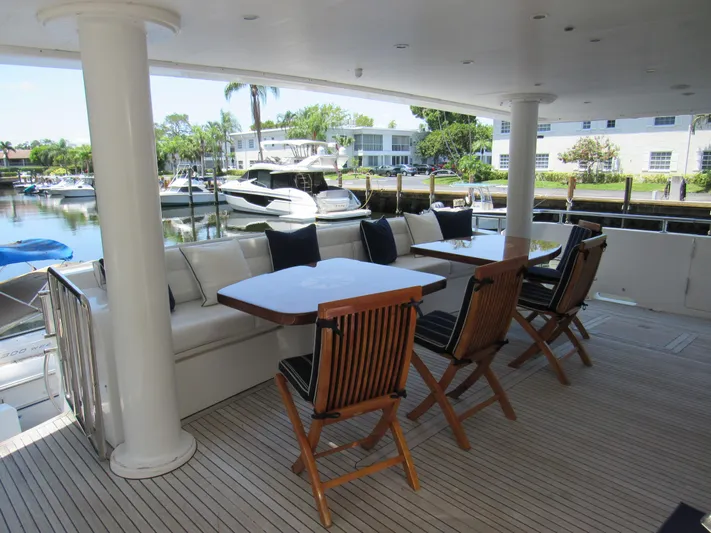 Sanctuary Yacht Photos Pics Outdoor seating area on a 2002 Hargrave Raised Pilothouse yacht, featuring wooden chairs and tables.