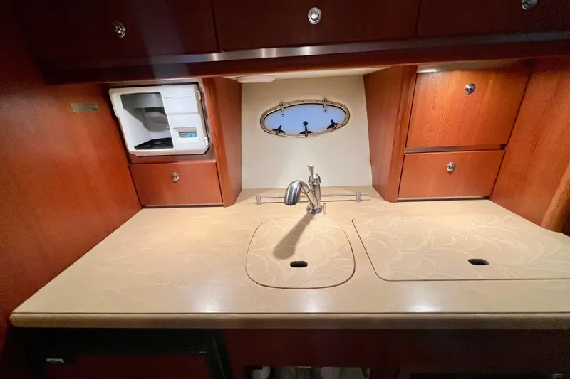 Blue Pearl Yacht Photos Pics 2005 Tiara Yachts 3200 Open kitchen with sink, wooden cabinets, and porthole window.