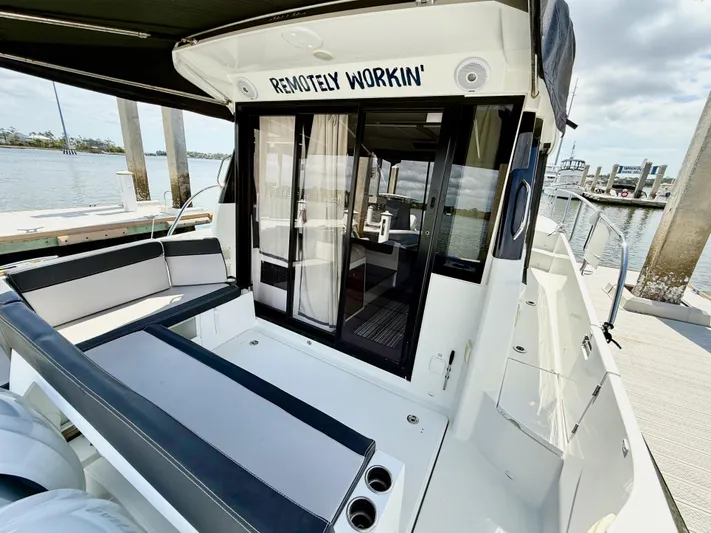 Remotely Workin' Yacht Photos Pics 2022 Jeanneau NC 1095 Coupe boat with seating area, docked by the water.