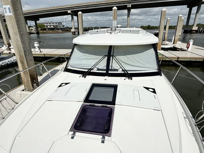 Remotely Workin' Yacht Photos Pics 2022 Jeanneau NC 1095 Coupe docked near a bridge, showcasing sleek design and spacious deck.