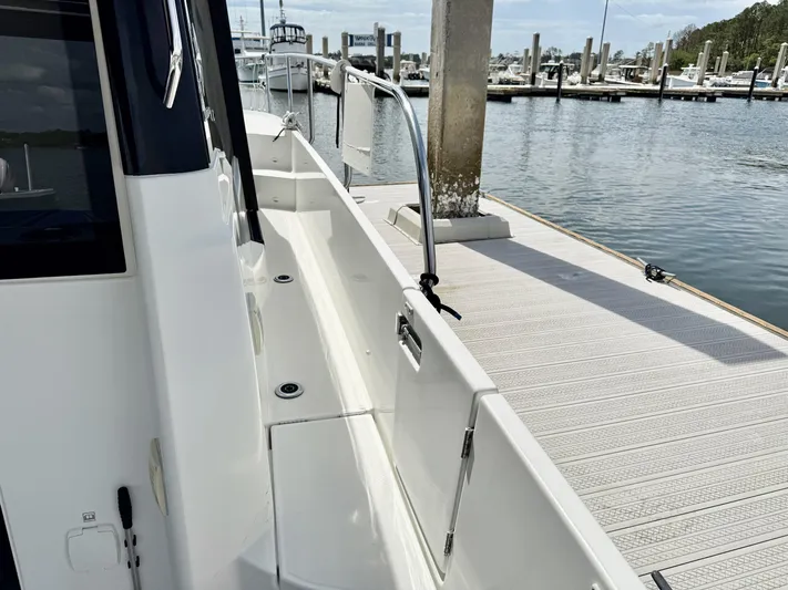 Remotely Workin' Yacht Photos Pics 2022 Jeanneau NC 1095 Coupe docked at marina, showcasing sleek side deck design.