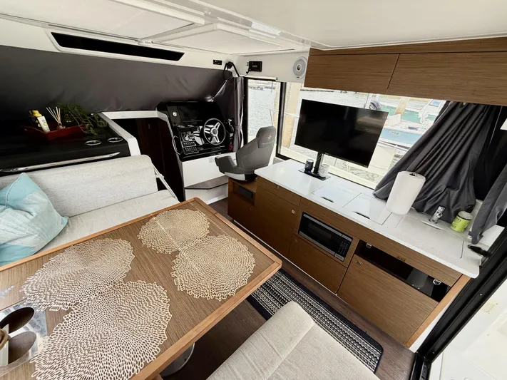 Remotely Workin' Yacht Photos Pics Interior of 2022 Jeanneau NC 1095 Coupe with modern seating, table, and entertainment system.