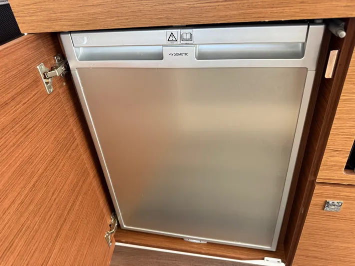 Remotely Workin' Yacht Photos Pics Built-in fridge on 2022 Jeanneau NC 1095 Coupe boat, wooden cabinetry.