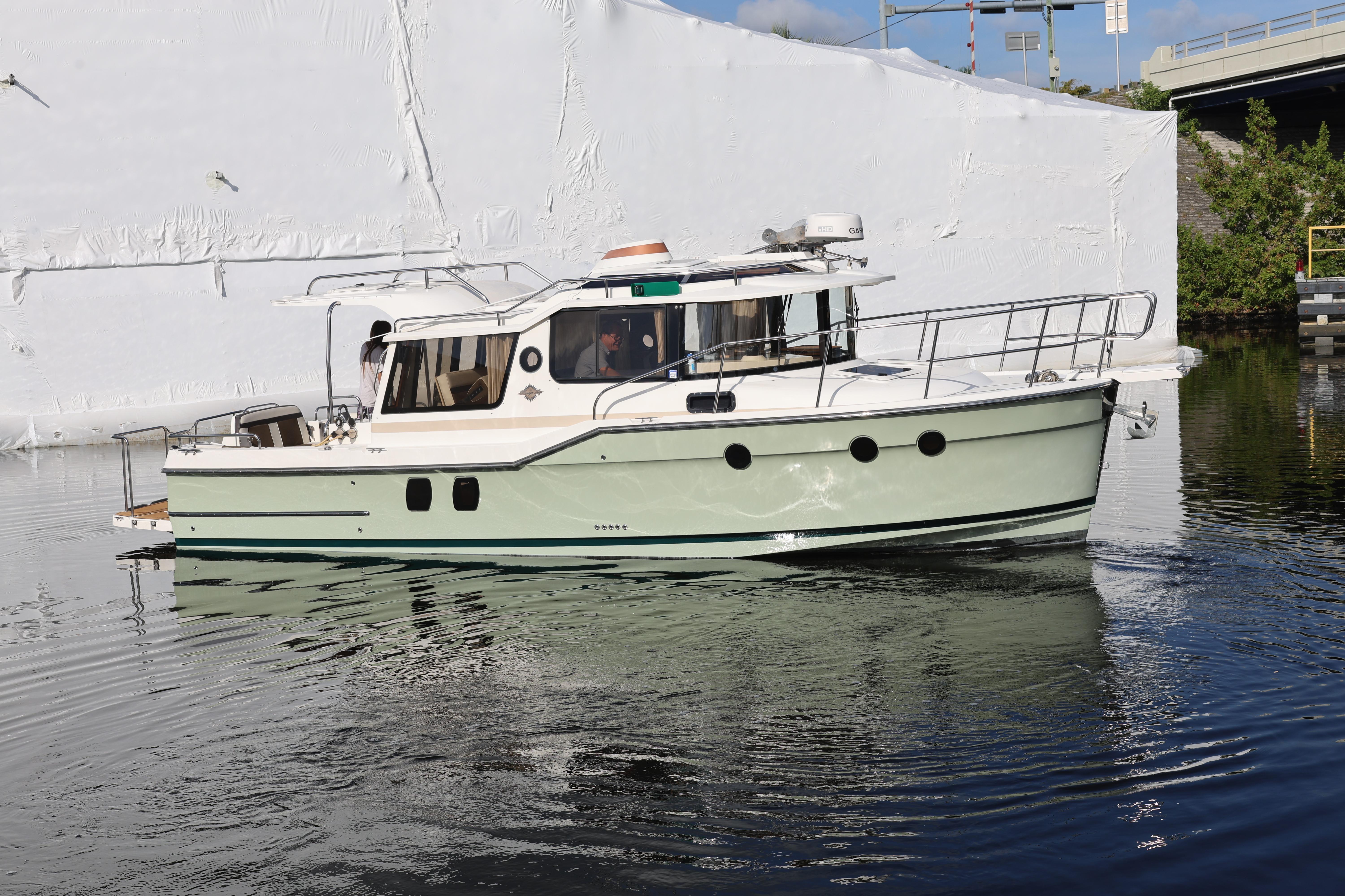 2015 Ranger Tugs R-29 S boat cruising on calm water near a white structure.