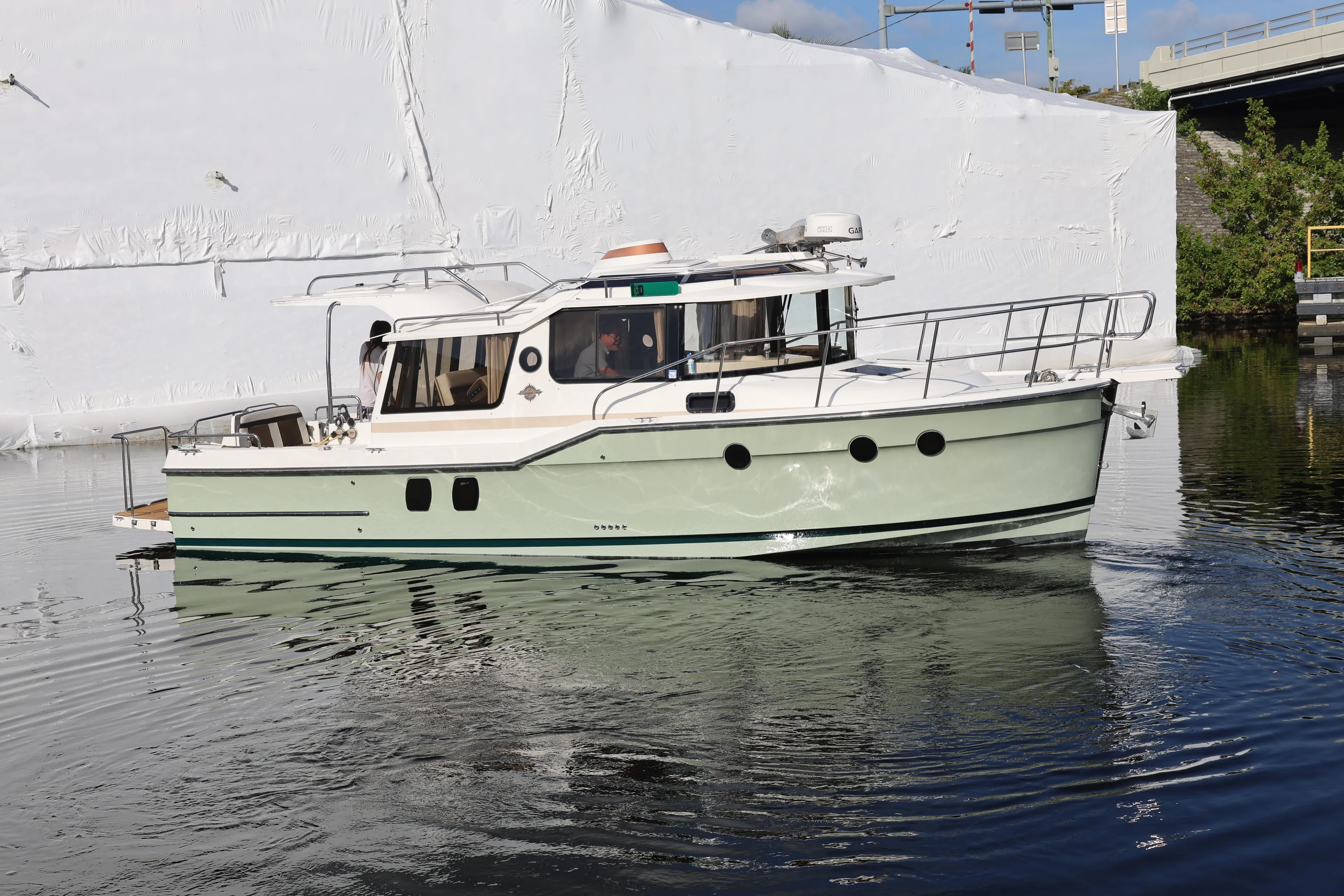 2015 Ranger Tugs R-29 S boat cruising on calm water near a white structure.