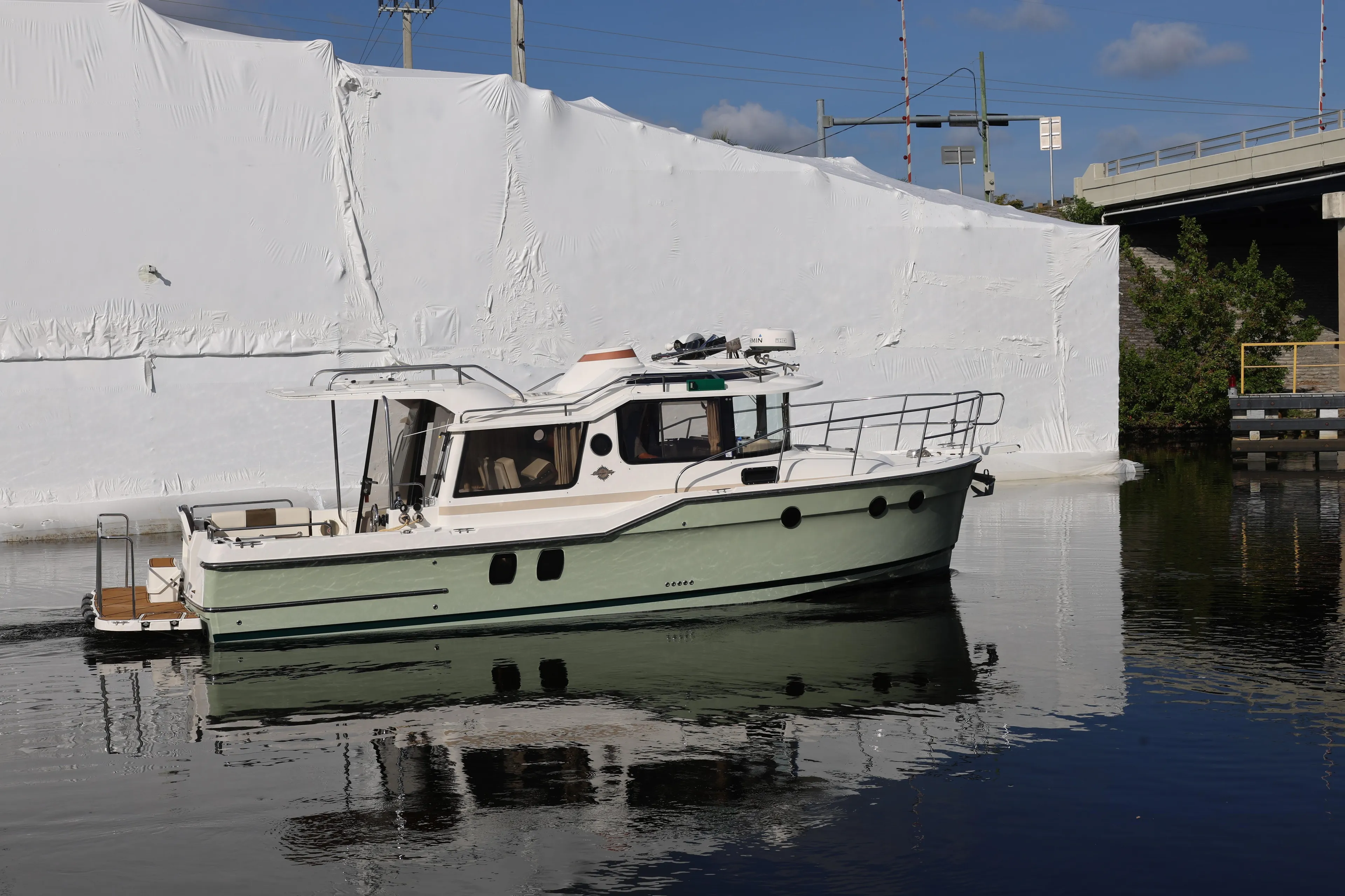 2015 Ranger Tugs R-29 S boat on calm water near a white structure.
