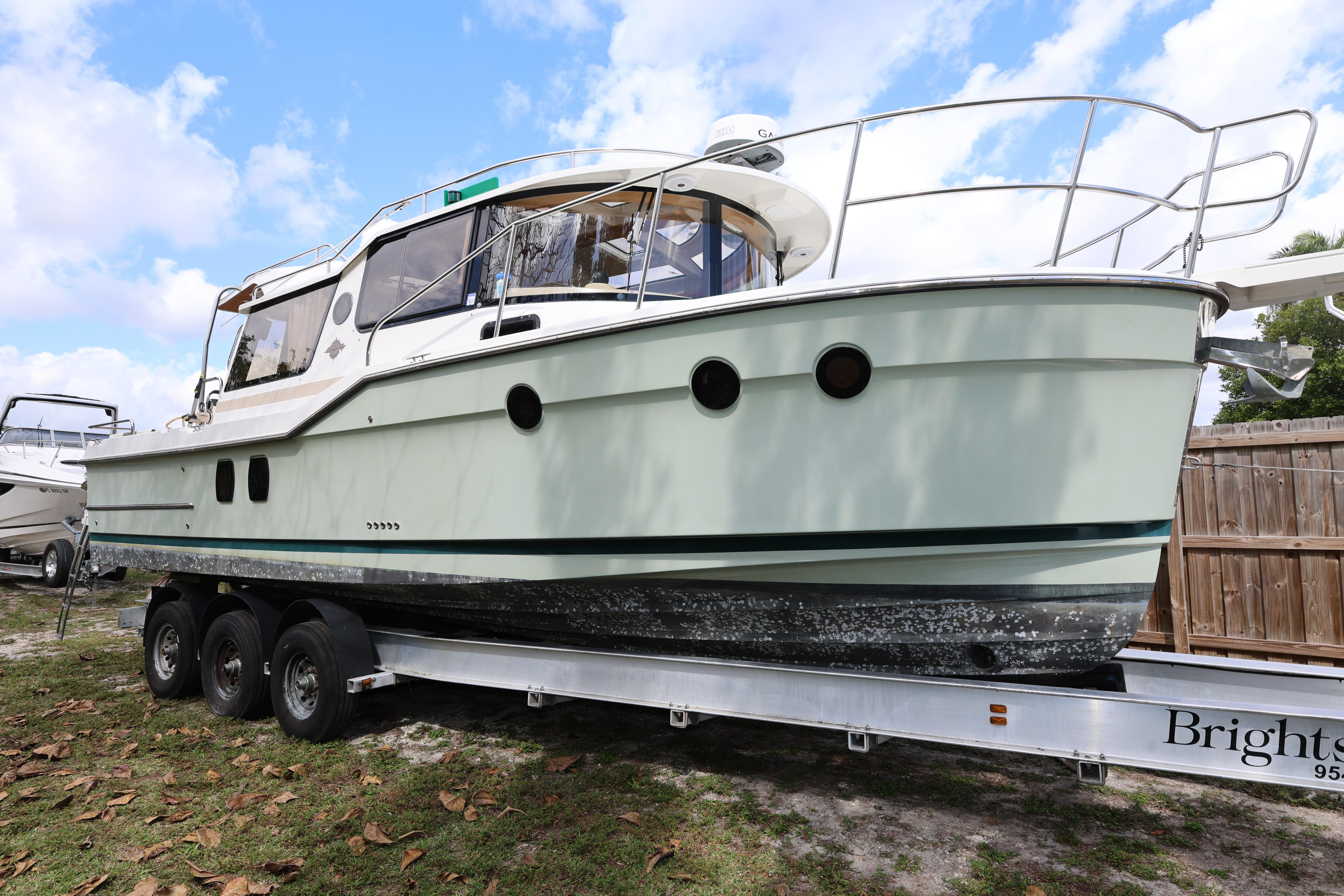 2015 Ranger Tugs R-29 S boat on trailer, parked outdoors under blue sky.