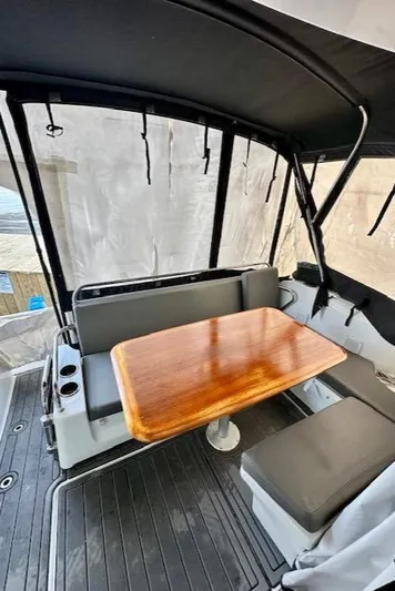  Yacht Photos Pics 2019 Beneteau Antares 27 boat interior with seating and wooden table.