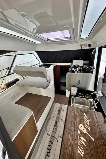  Yacht Photos Pics Interior of a 2019 Beneteau Antares 27 boat, featuring seating, helm, and kitchenette.
