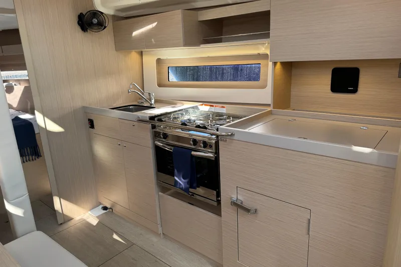 Show Boat! Special Pricing Yacht Photos Pics Modern kitchen interior of 2024 Beneteau Oceanis 37.1 yacht with sleek wood finish.