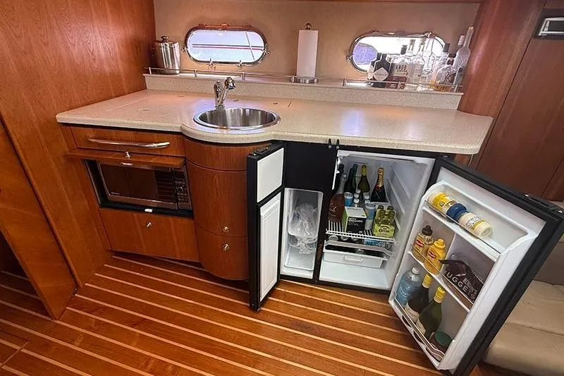 Ritz Karllton Too Yacht Photos Pics 2008 Tiara Yachts 3900 Sovran galley with open fridge, sink, and wooden flooring.