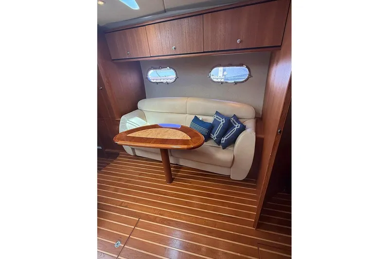 Ritz Karllton Too Yacht Photos Pics 2008 Tiara Yachts 3900 Sovran interior with wooden table, beige sofa, and decorative pillows.