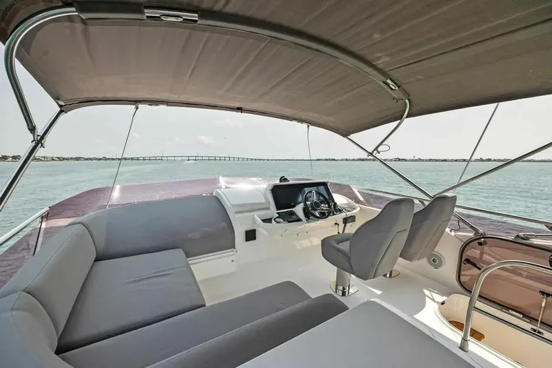  Yacht Photos Pics Flybridge view of 2018 Princess F49 yacht with seating and helm, overlooking water.