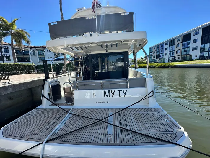 My Ty Yacht Photos Pics 2023 Beneteau Swift Trawler 48 docked, rear view, sunny day, waterfront setting.