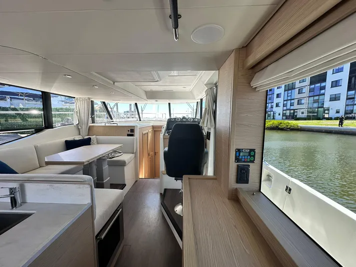 My Ty Yacht Photos Pics 2023 Beneteau Swift Trawler 48 interior with modern seating and helm, near waterfront.