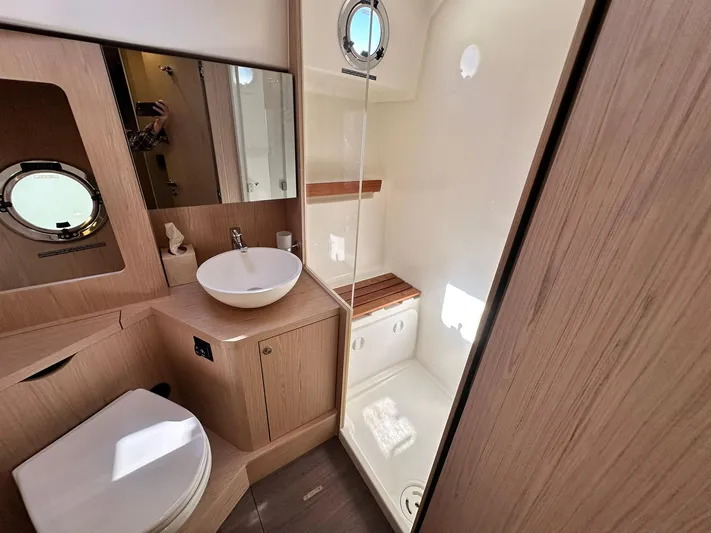 My Ty Yacht Photos Pics 2023 Beneteau Swift Trawler 48 bathroom with modern fixtures, wood accents, and porthole window.