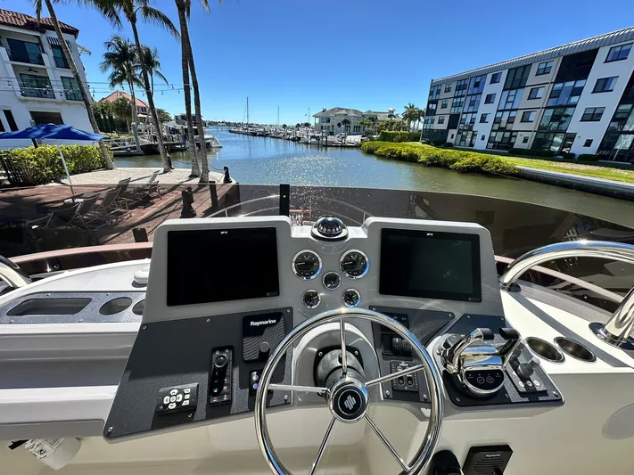 My Ty Yacht Photos Pics 2023 Beneteau Swift Trawler 48 helm with dual screens, docked in a sunny marina.
