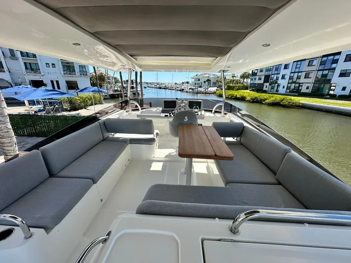 My Ty Yacht Photos Pics 2023 Beneteau Swift Trawler 48, spacious deck with seating, docked near waterfront buildings.