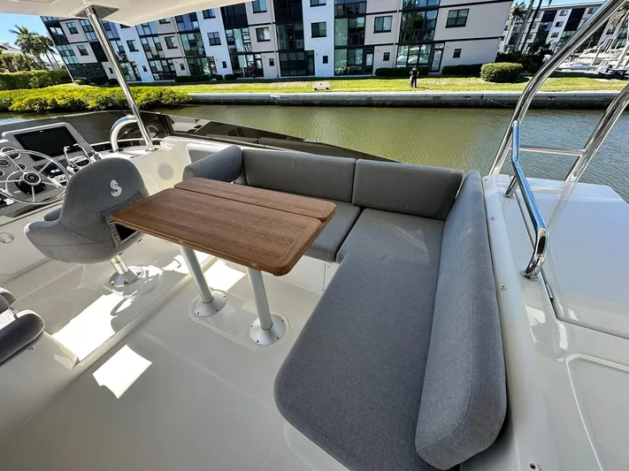 My Ty Yacht Photos Pics 2023 Beneteau Swift Trawler 48, outdoor seating area with table, near waterfront buildings.