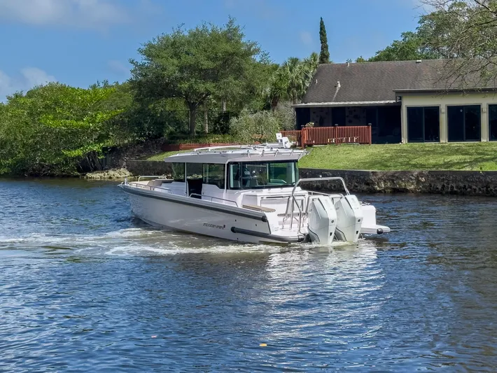  Yacht Photos Pics 2024 Axopar 37XC CROSS CABIN BRABUS Trim cruising on a scenic river near a house.