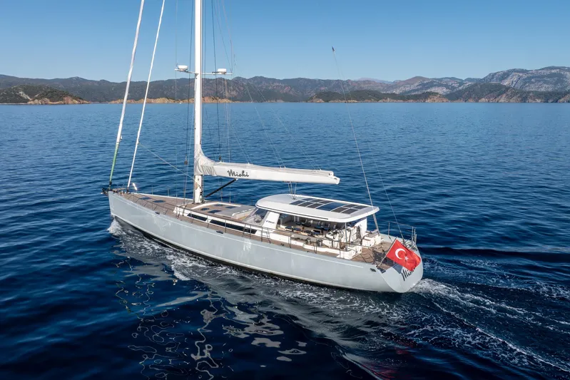 Mishi Yacht Photos Pics Sailing yacht "Mishi 88" cruising in clear blue waters, Turkish flag, mountainous coastline.