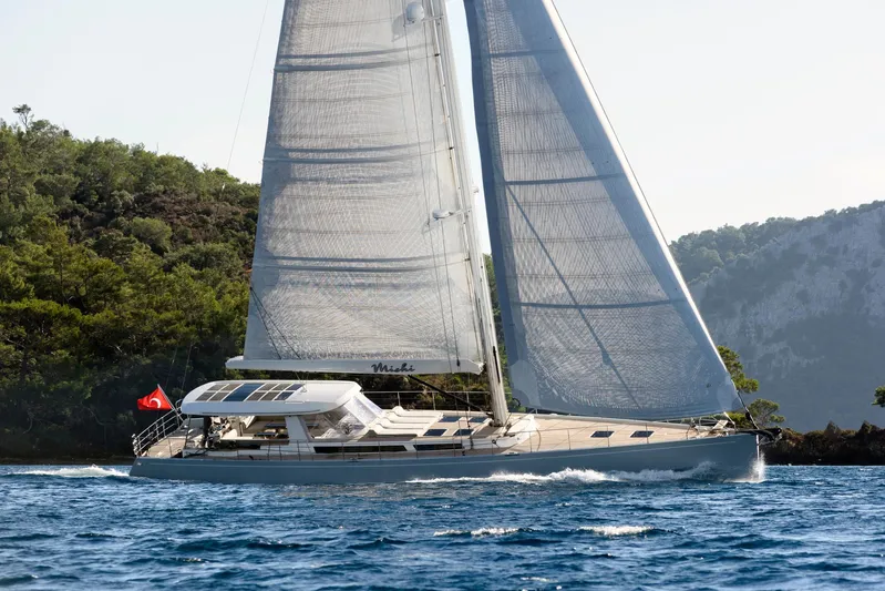 Mishi Yacht Photos Pics Sailing yacht "Mishi 88" gliding on water, surrounded by lush greenery, 2018 model.