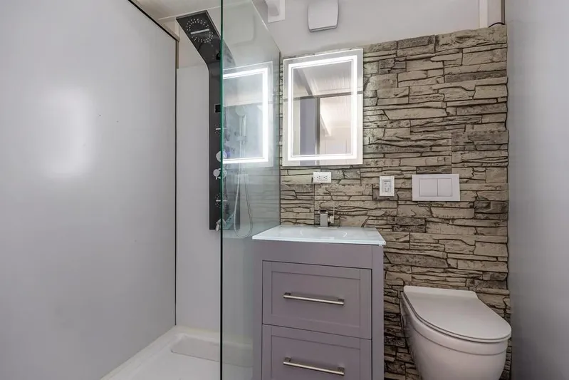  Yacht Photos Pics Modern bathroom with stone accent wall, illuminated mirror, and sleek fixtures, 2023 Modern Struktures MS 400.