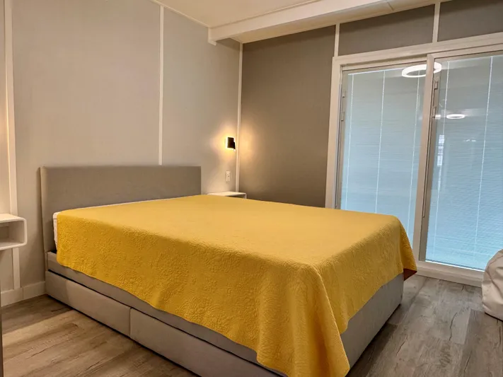  Yacht Photos Pics Modern bedroom with yellow bedspread, gray walls, and natural light from window blinds.