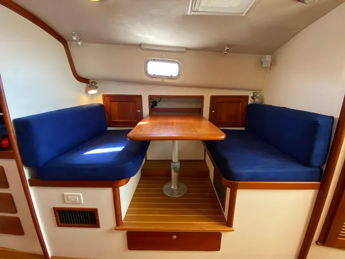 Red Castles Yacht Photos Pics Interior dining area of 2000 Little Harbor 42 Whisper Jet with blue cushions and wooden table.
