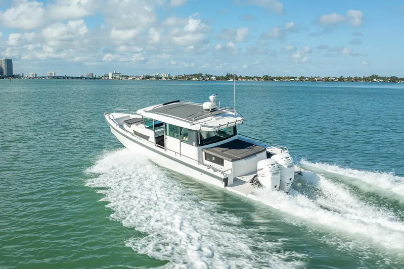  Yacht Photos Pics 2017 Axopar 37 XC Cross Cabin cruising on open water, city skyline in background.