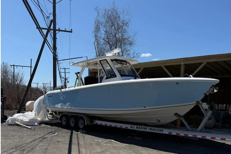  Yacht Photos Pics 2024 Pursuit S 328 Sport boat on trailer, parked outdoors under clear sky.