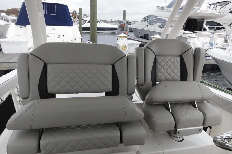 Yacht Photos Pics 2024 Pursuit S 328 Sport boat seats with quilted gray upholstery at a marina.