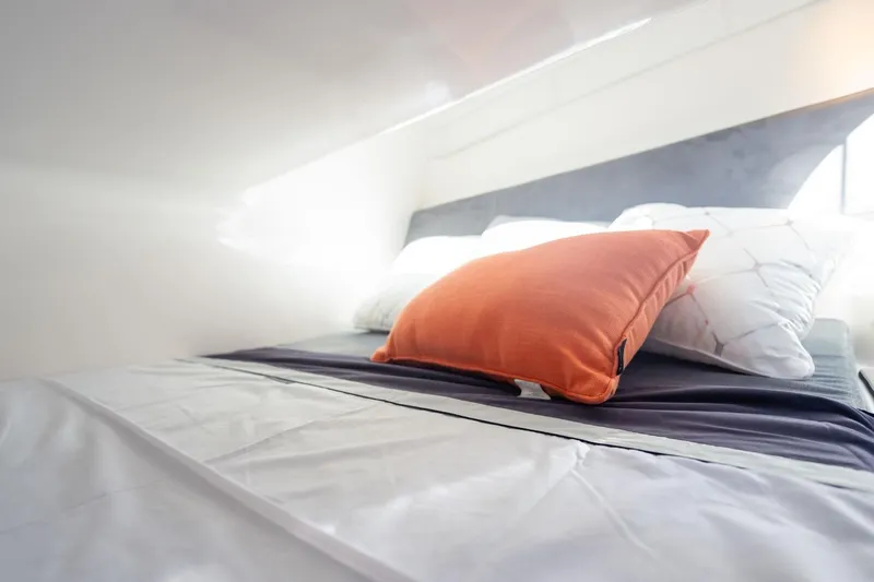  Yacht Photos Pics Modern bed with orange and white pillows in a Hanover 305, 2026 model.