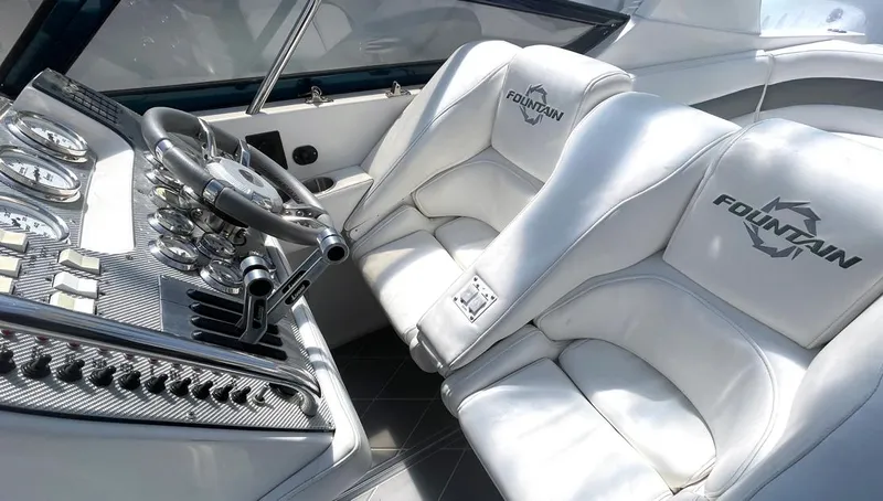  Yacht Photos Pics 2002 Fountain 38 Express Cruiser cockpit with white leather seats and sleek control panel.